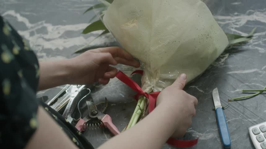 A florist ties a ribbon on a bouquet