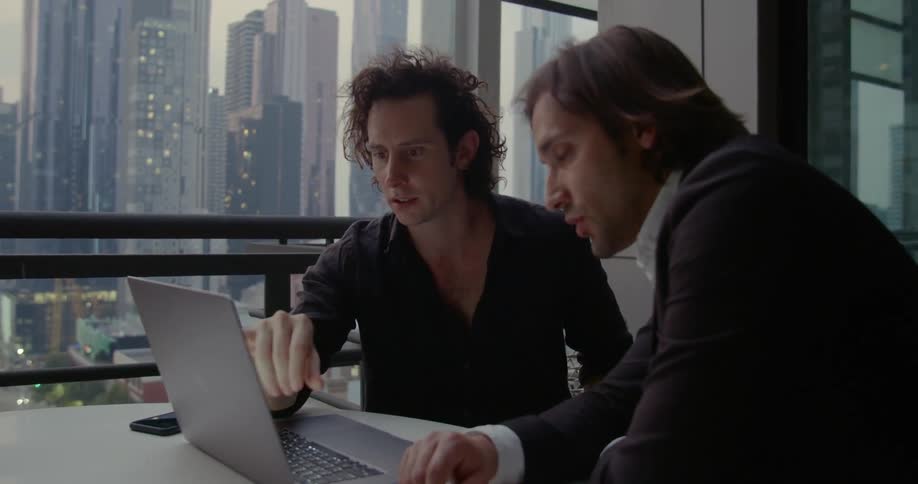 Two men are looking at a laptop in an office building downtown