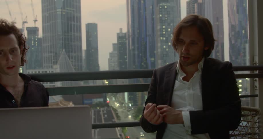 Two men talk in the office looking at a laptop