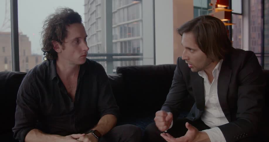 Two men sitting on a sofa having a business discussion gesturing with their hands