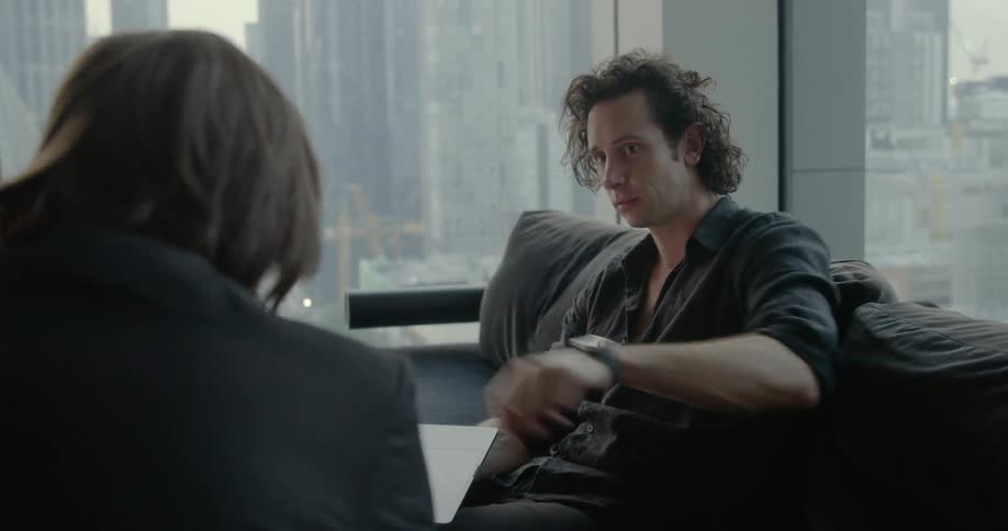 Two men collaborate over laptop near windows with view of the city