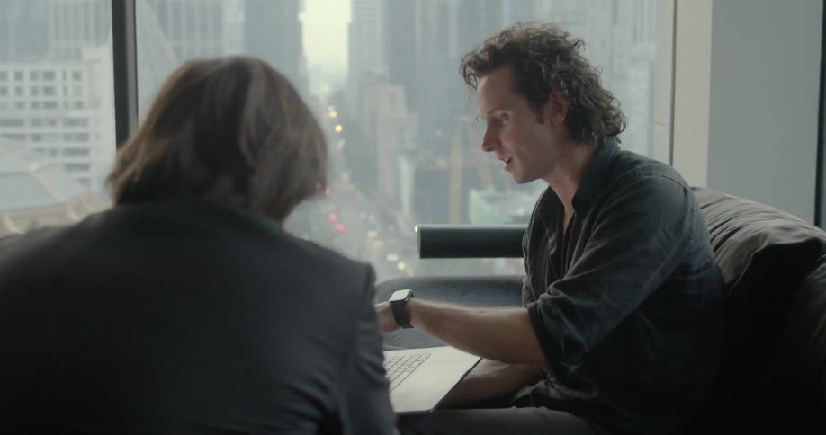 Two businessmen sitting on the couch uses a laptop in the office