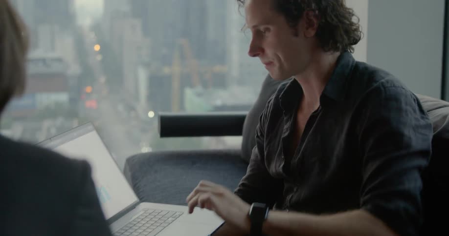 Two people are in an office typing on a laptop