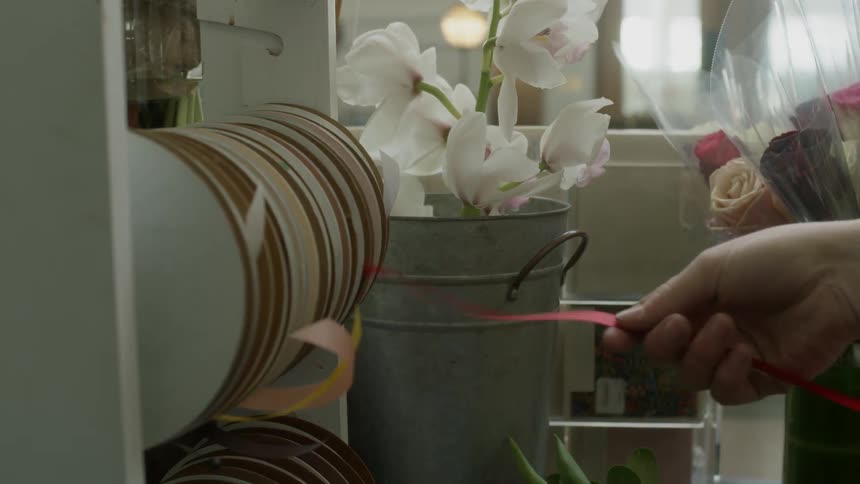 A white woman pulls red ribbon off of a reel