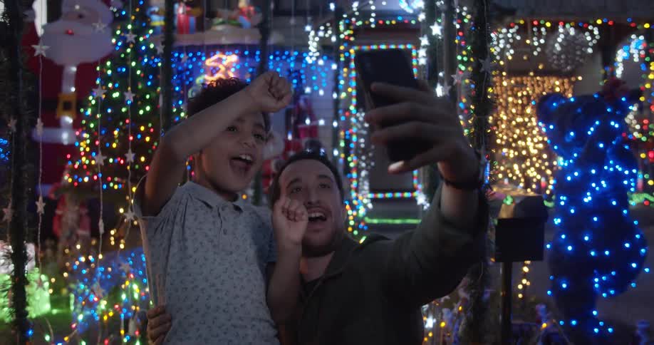 Father and son take a selfie with the christmas lights in the background