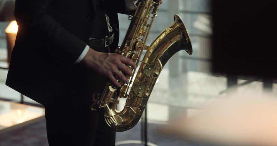 A man plays the saxophone in a large office style room