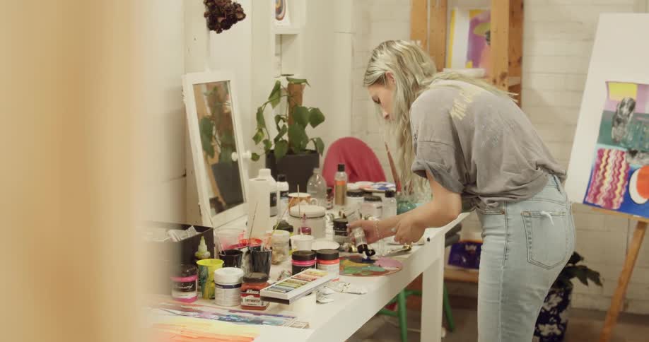 A young woman puts paint on a palette