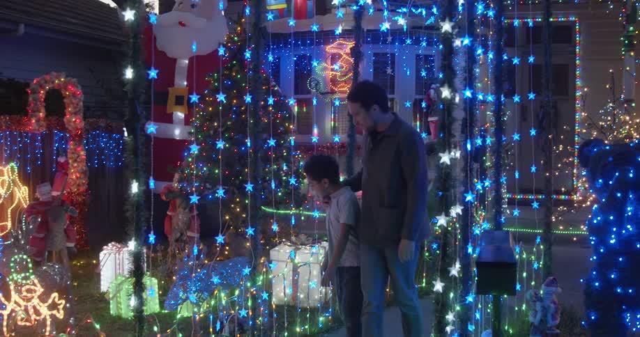A man walks through a christmas light display with his son