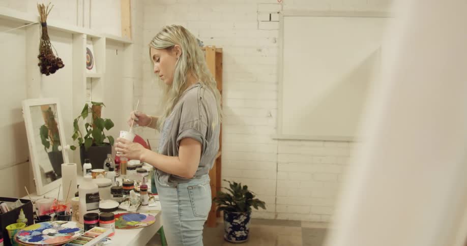 A woman mixes paint in an art studio
