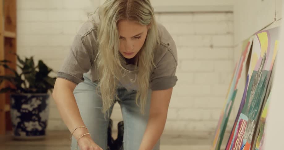 A woman pours paint onto a blank canvas