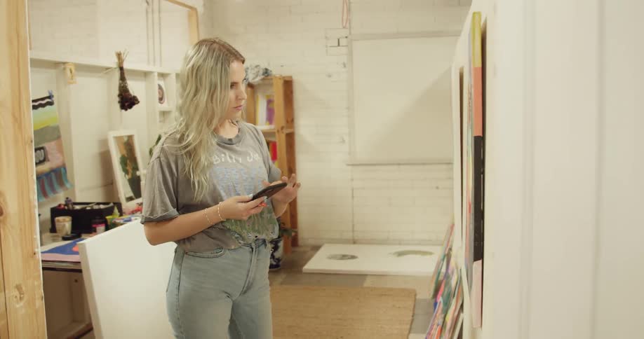 A woman using a smartphone while looking at a painting