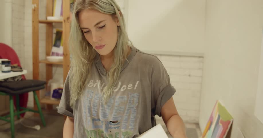 A woman looks over a painting that shes holding