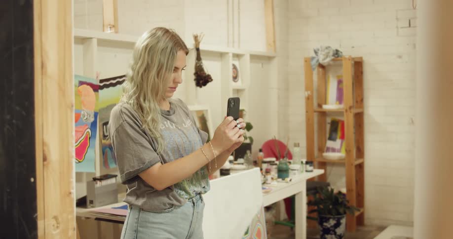 Woman filming a video in her art studio with a smartphone