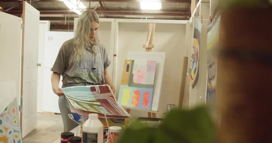 A young woman looks through a pile of paintings