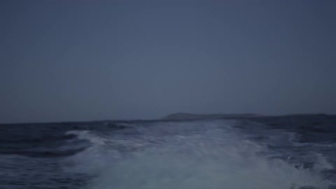 Looking back from onboard a fast boat leaving a wide and foaming wake in the distance