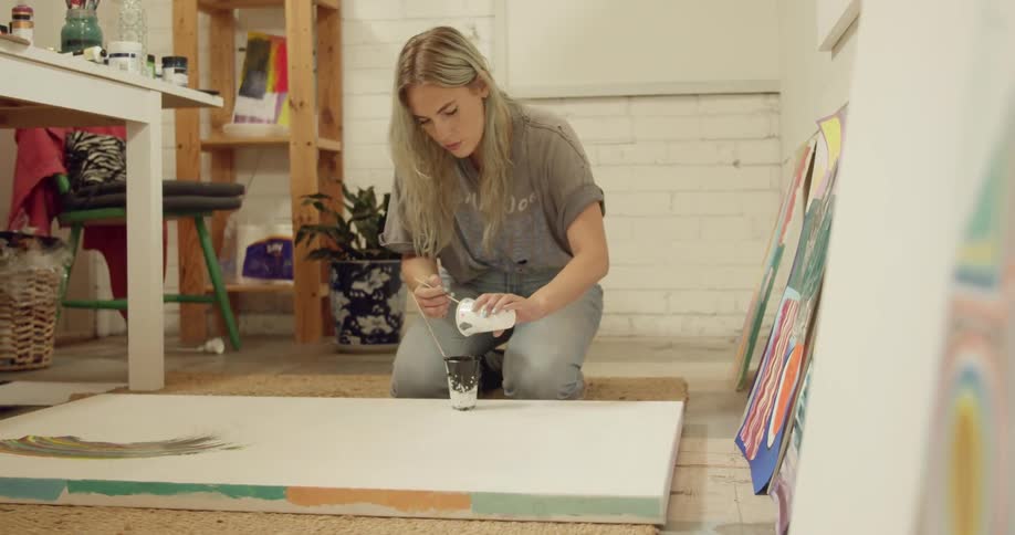 A woman pours paint in to a cup