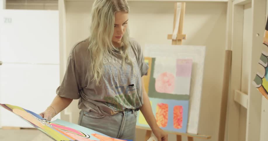 A woman looks through a pile of paintings