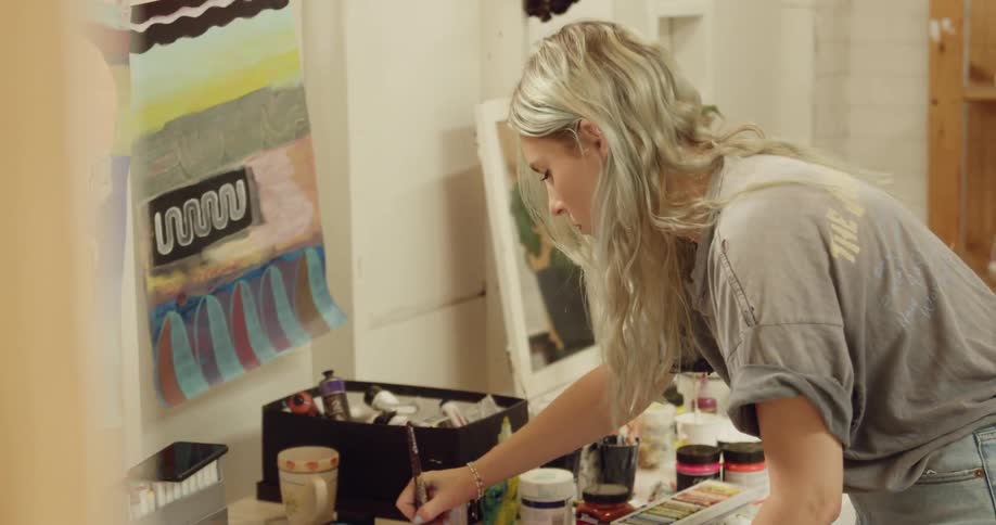 The woman painting on a paper placed on a table