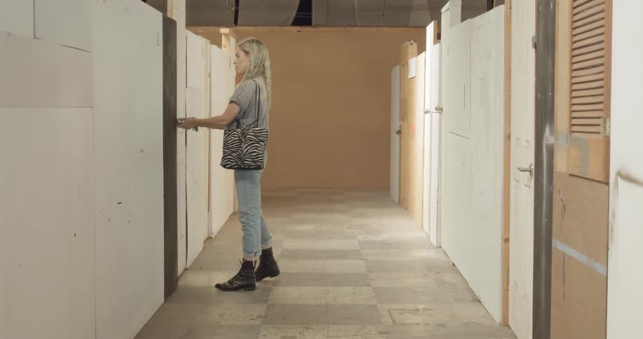 A woman walks down a hallway and unlocks a door