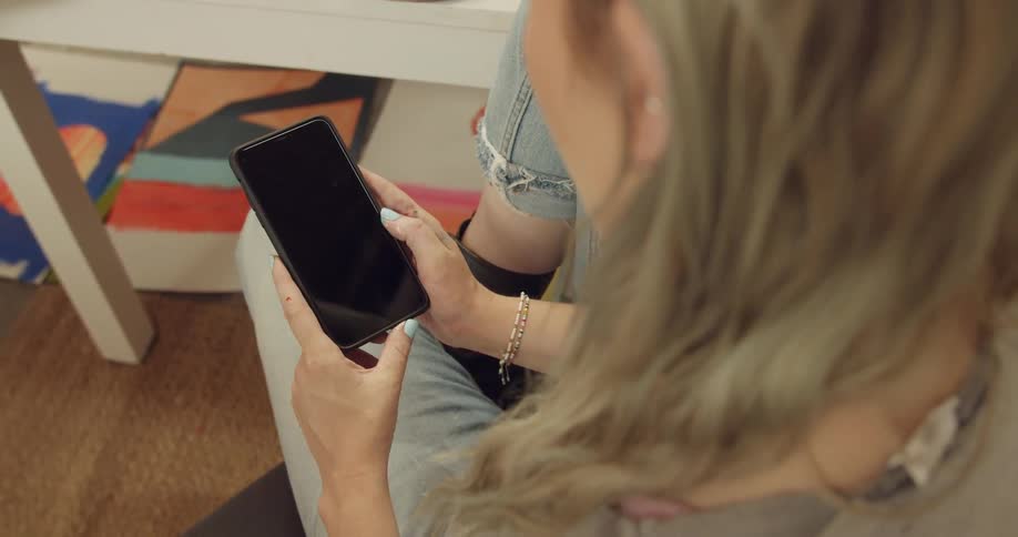 A woman sitting down holding a smart phone