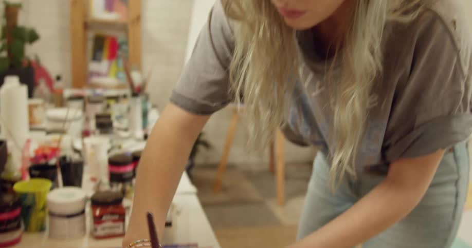 A female artist brushes blue paint onto paper