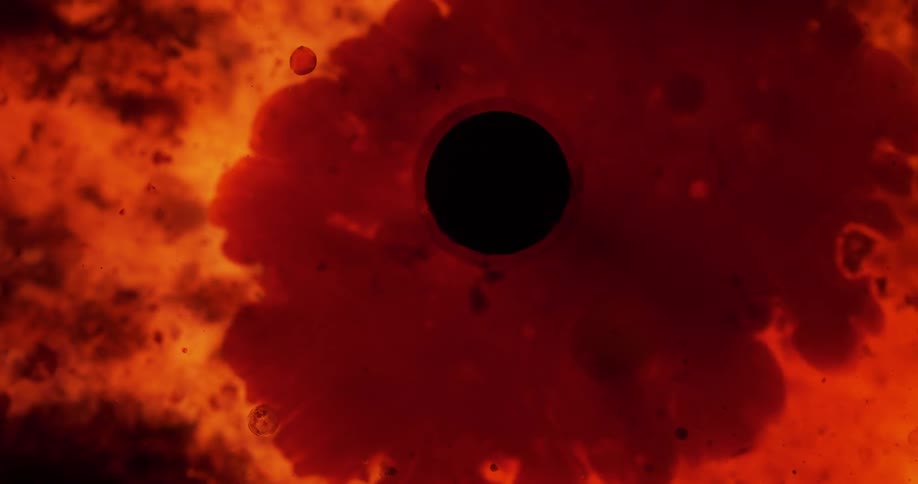A black orb center of red and orange clouds
