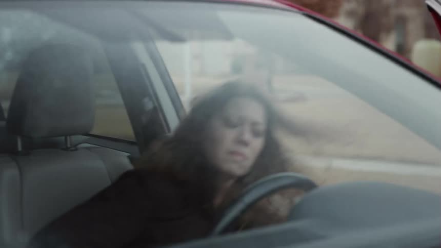 A woman climbs into the drivers seat of a car and starts crying