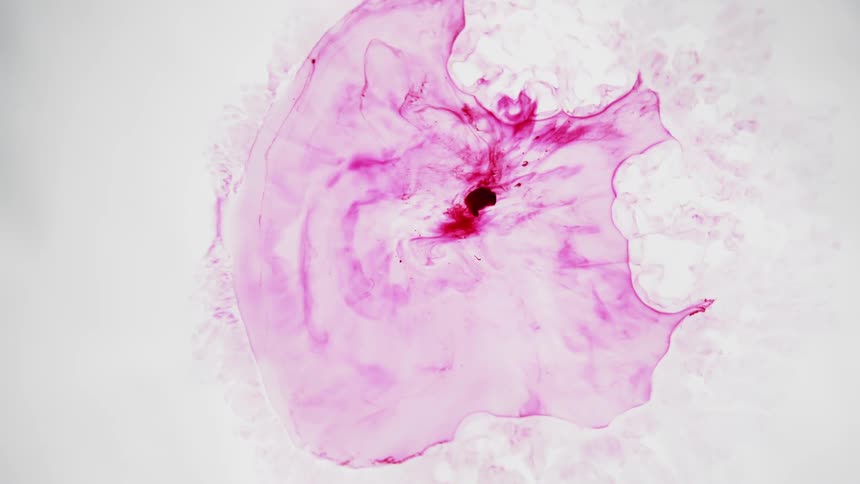 Purple colored ink moves against a white background