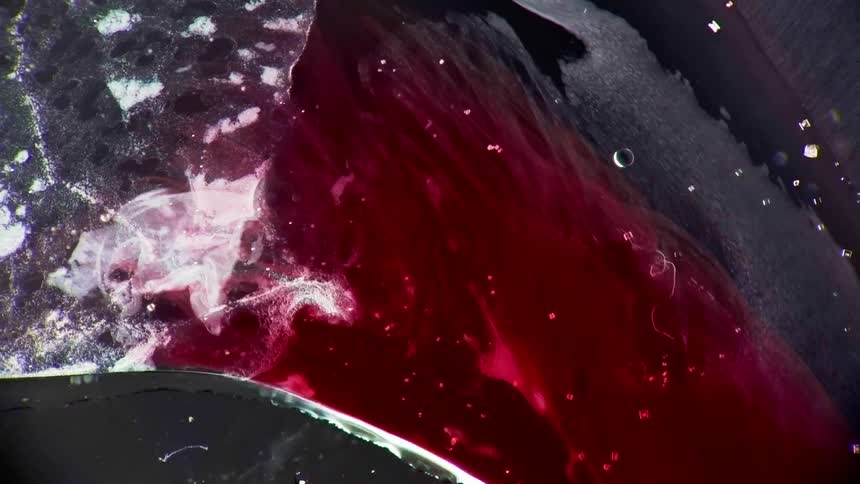 Red and grey liquids spill together to form a pattern