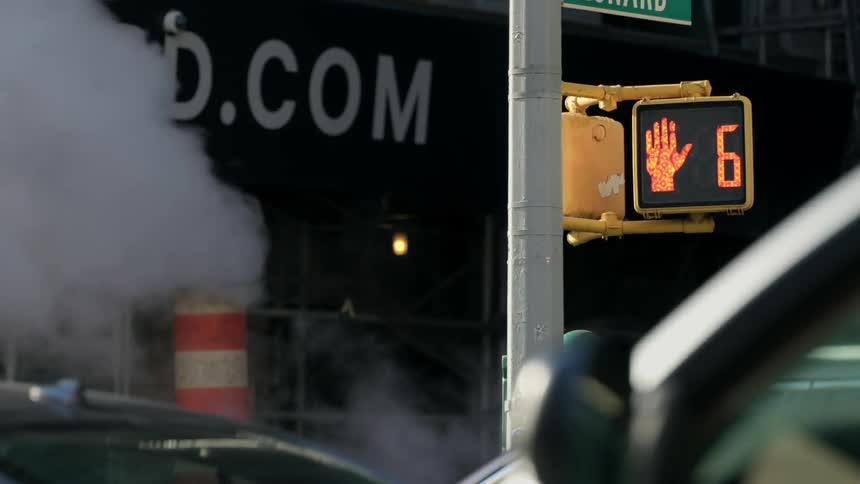 A red traffic crossing light counts down from ten on a busy city street