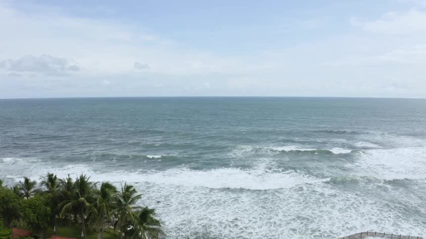 Ocean waves rolling into the beach next to a resort