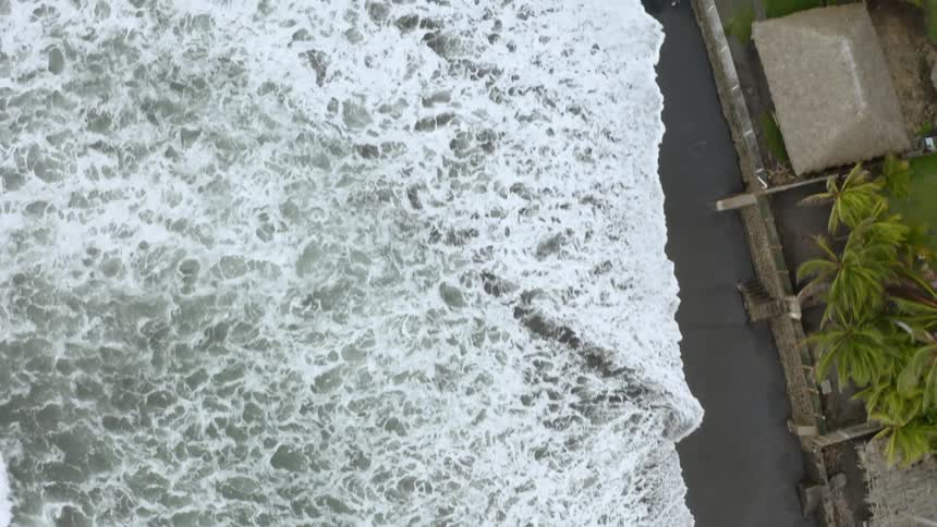 Foamy waves roll up against a shoreline
