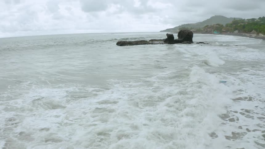 A person rides a wave to the shoreline