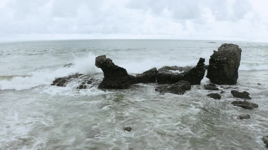 A rocky shore with the sky and trees in the background