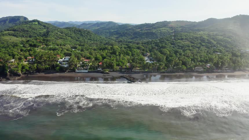 The small waves move towards the houses on the coast