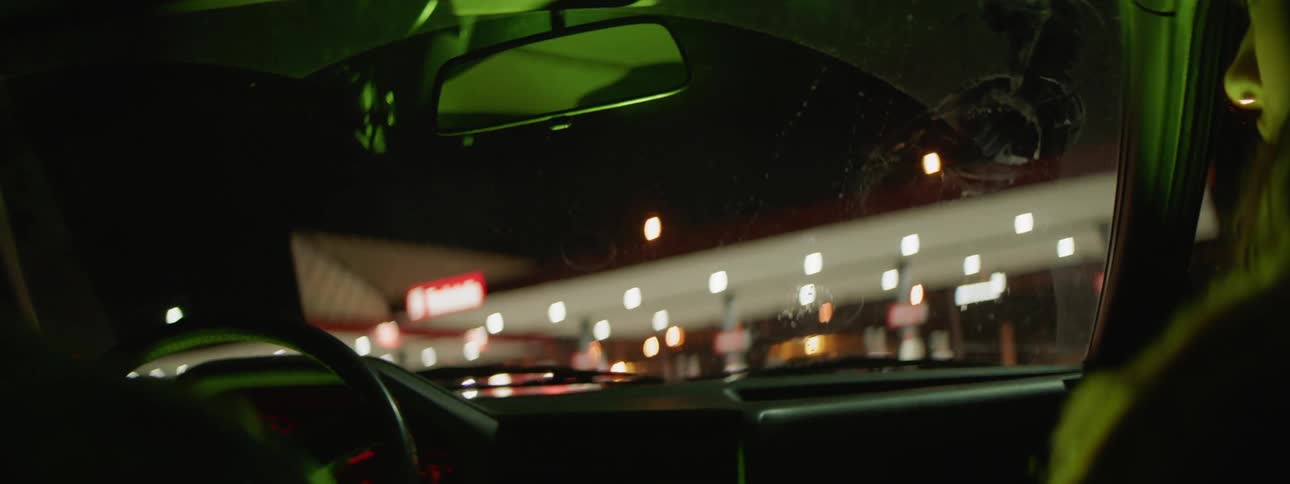 People drive a car through a gas station parking lot
