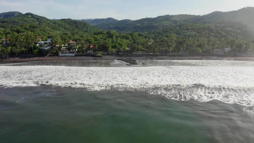 The coastal shore with waves trees and houses