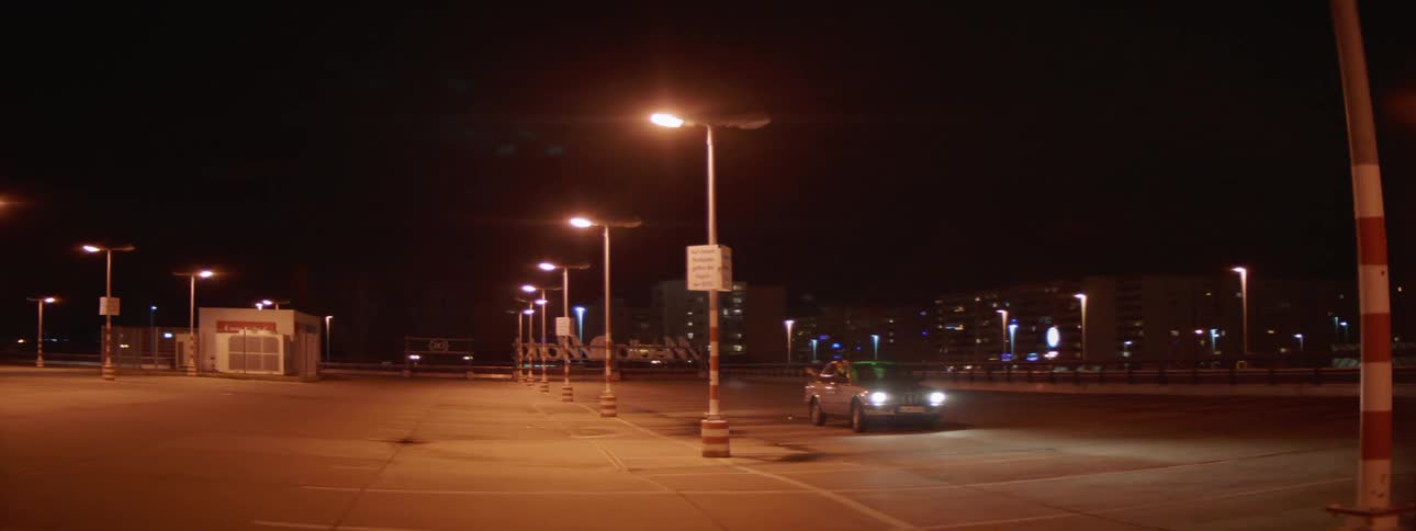 A car weaves in a parking lot at night