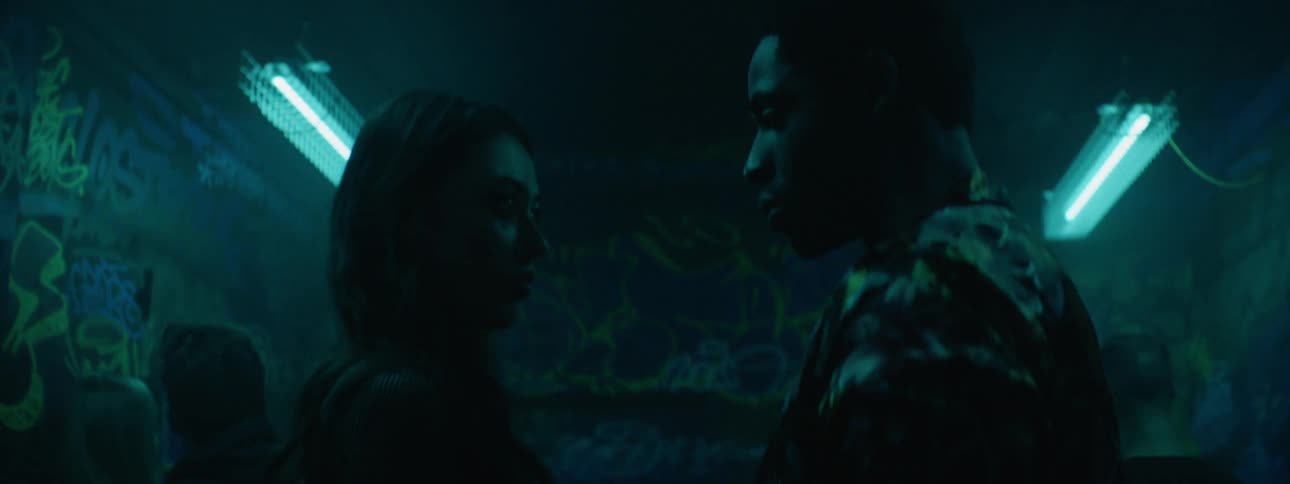 Couple standing looking at each other indoors surrounded by flashing lights