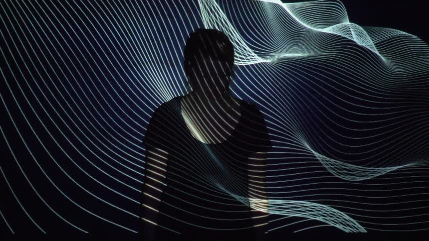 A woman stands as flashing lights reflect on her