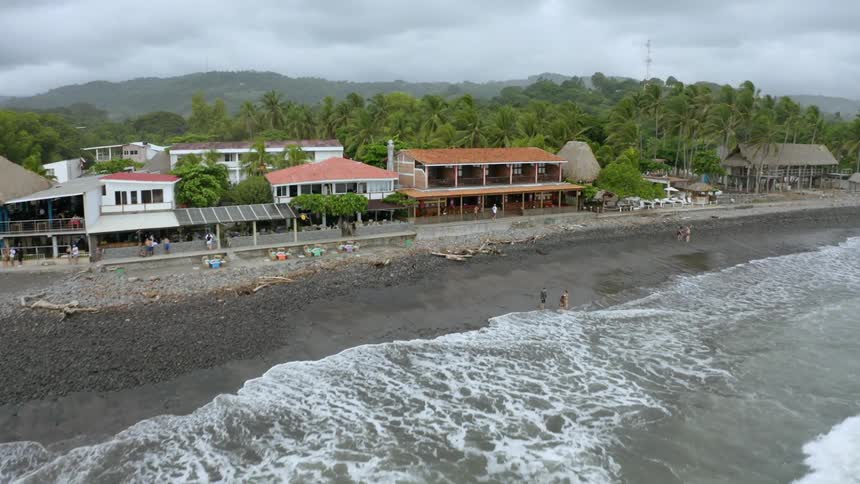 The ocean waves splash toward the buildings
