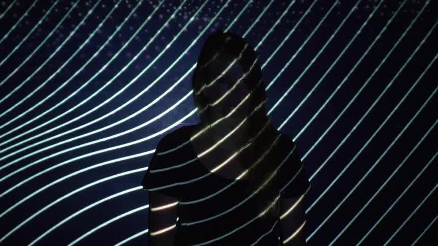 Lights lines and images are projected on a womans face and torso