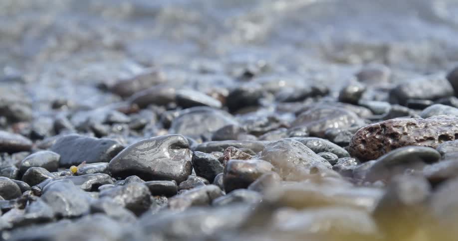 Small waves crash against the beach with pebbles