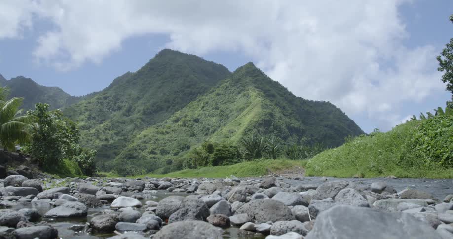 Large stones fill riverbed with forest covered mountains in background