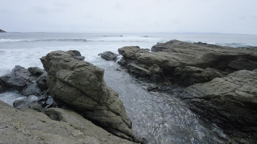 The tide comes in and pools in between large rock formations on the coast