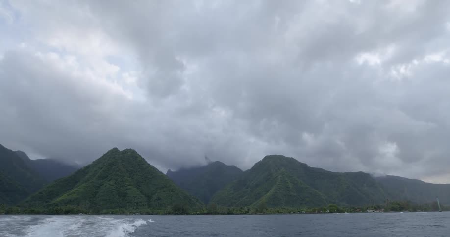 Mountain peaks off the coast of an ocean under cloudy skies