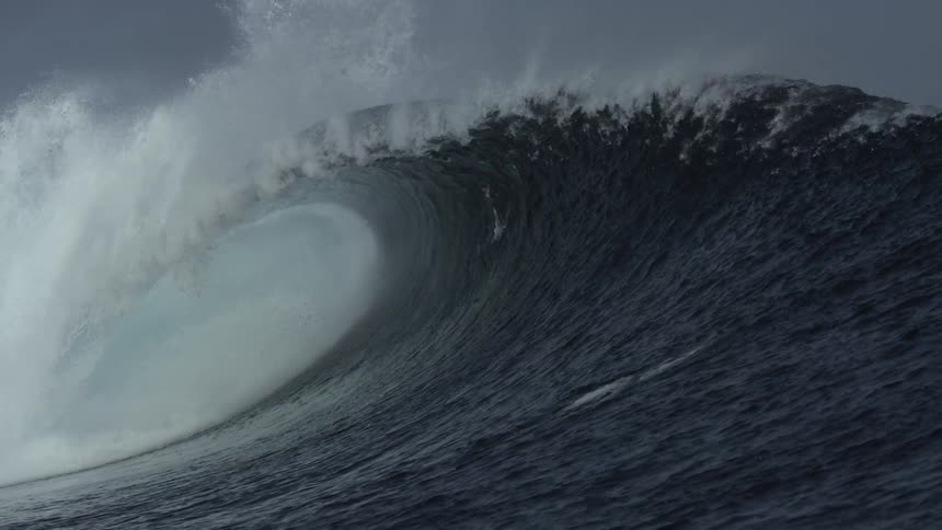 A giant wave rolls over two people in the water