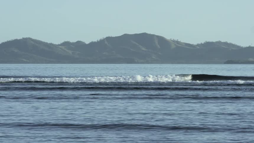Waves crash in the ocean near an island