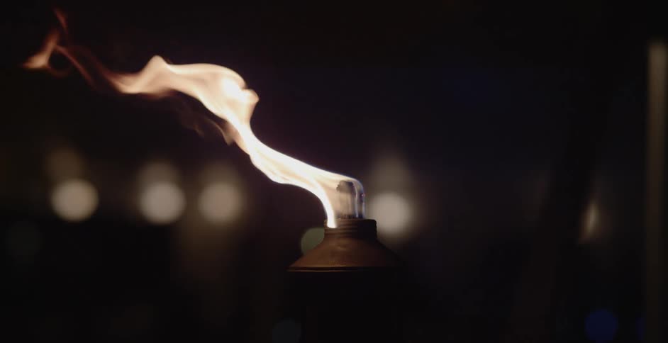 A flame is lighting a candle outdoors