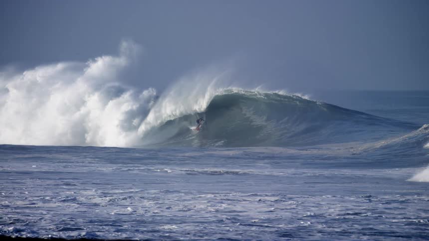Male surfer surfs a big wave in the sea during daylight